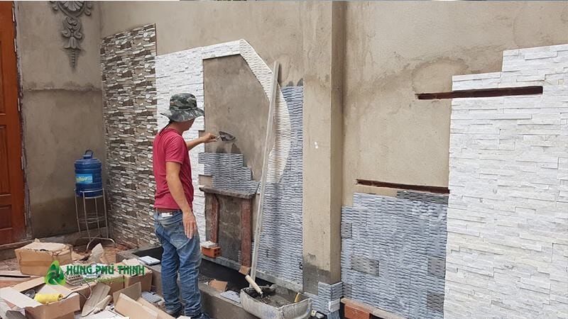 Công nhân đang ốp đá nghệ thuật bức tường trước nhà